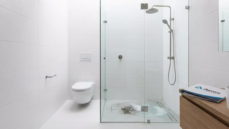 Banheiro moderno com vaso sanitário e chuveiro mostrando problema de drenagem